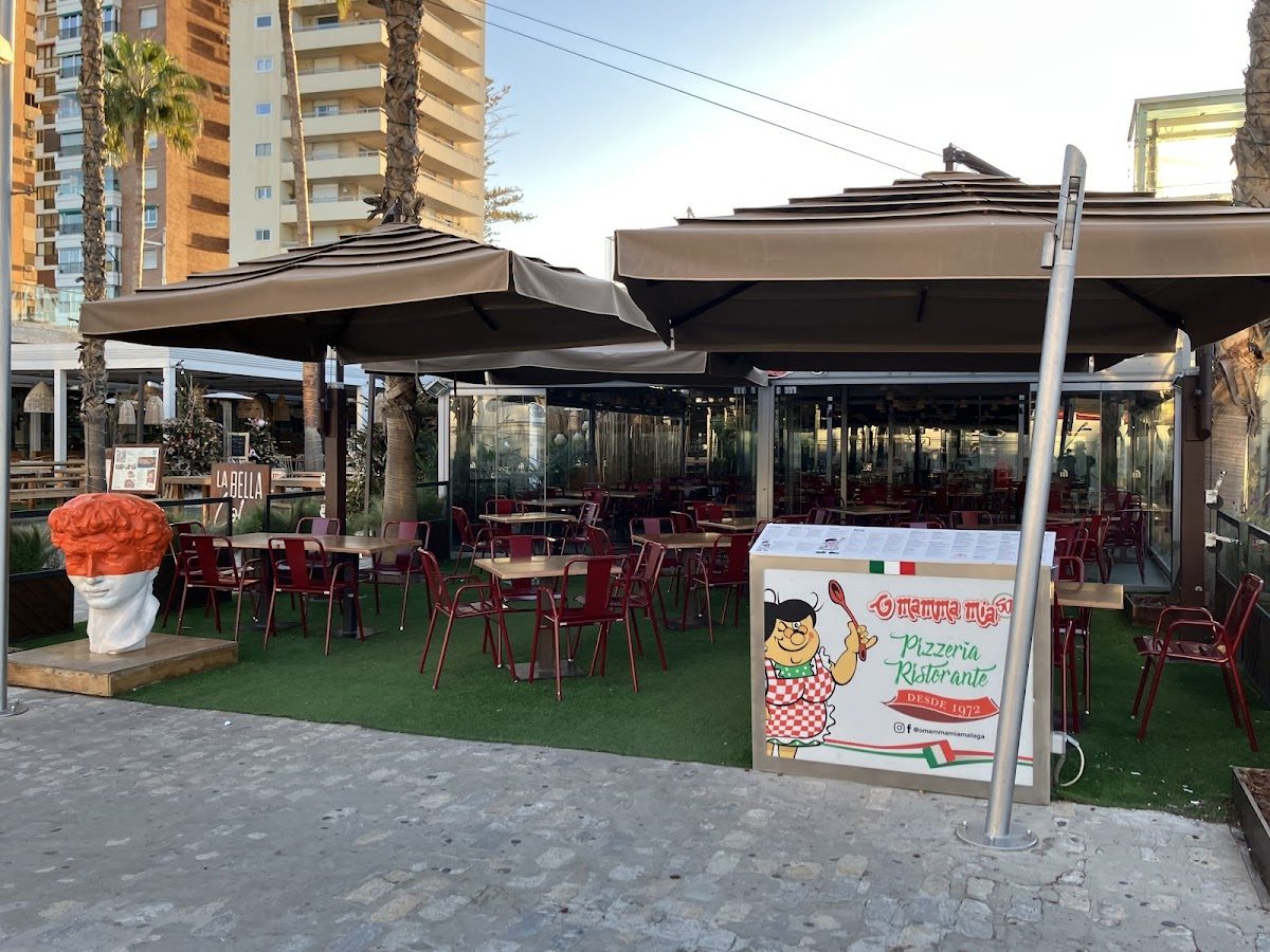 O Mamma Mia features outdoor seating with red chairs and a playful sign in Muelle Uno, Málaga.