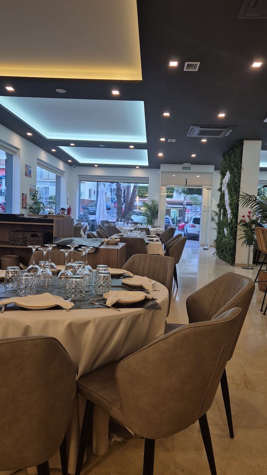 Interior of O Sole Mio Restaurante featuring elegant tables, chairs, and large windows with a view outside.