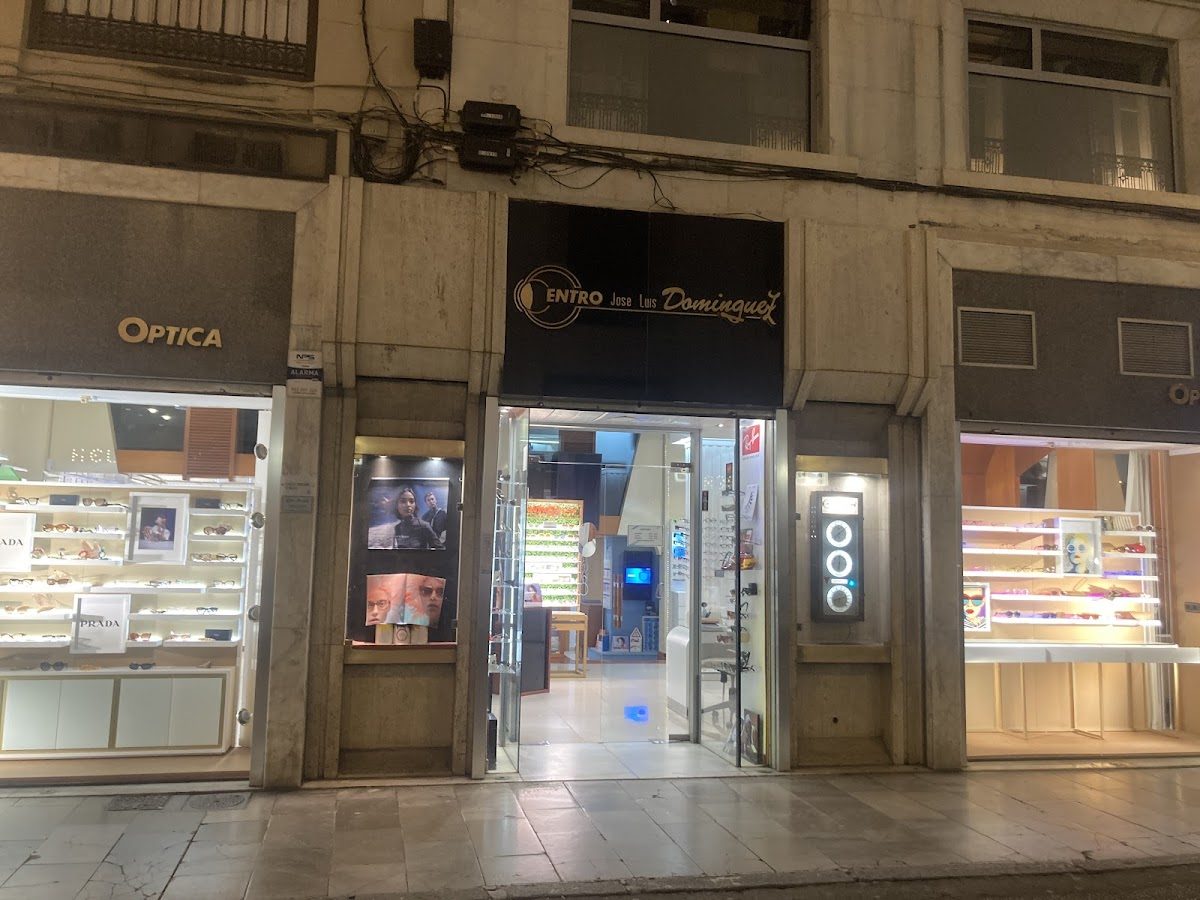 Fachada del Centro Óptico José Luis Domínguez SL con letreros iluminados y exhibidores de gafas.