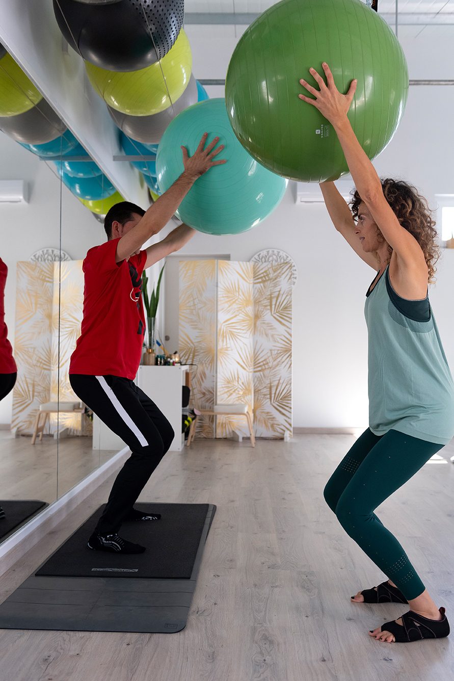 A fitness class at ORIGEN featuring two people exercising with large exercise balls.