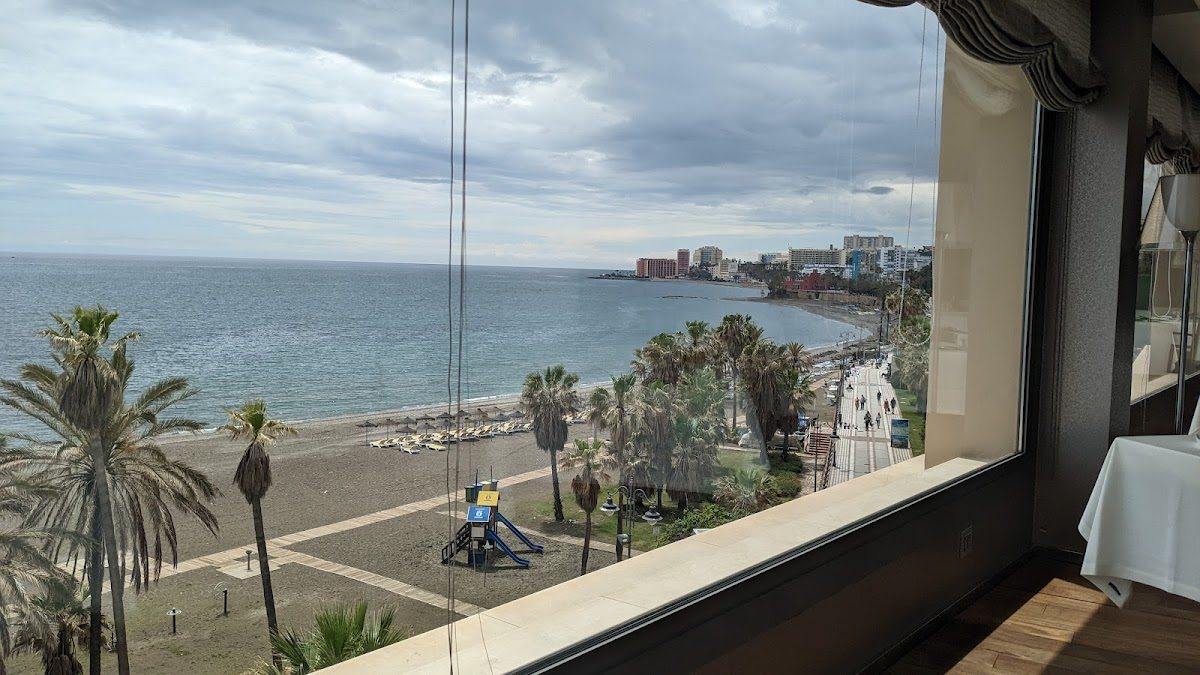 Vista desde el balneario Oshum que muestra la playa, las palmeras y el litoral de Benalmádena.