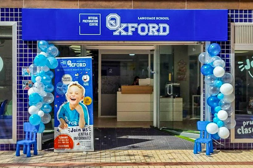 The entrance of Oxford Language School Málaga features blue and white balloons and a promotional banner.