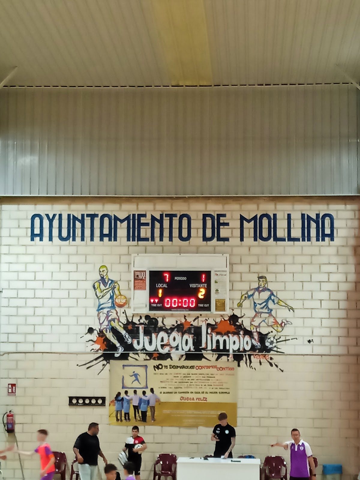 Vista interior del Pabellón de Mollina, que incluye un marcador y murales en las paredes que promueven el espíritu deportivo.