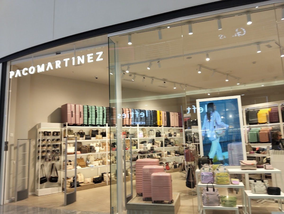 La tienda PACOMARTINEZ ofrece una variedad de bolsos y accesorios expuestos en sus estantes.