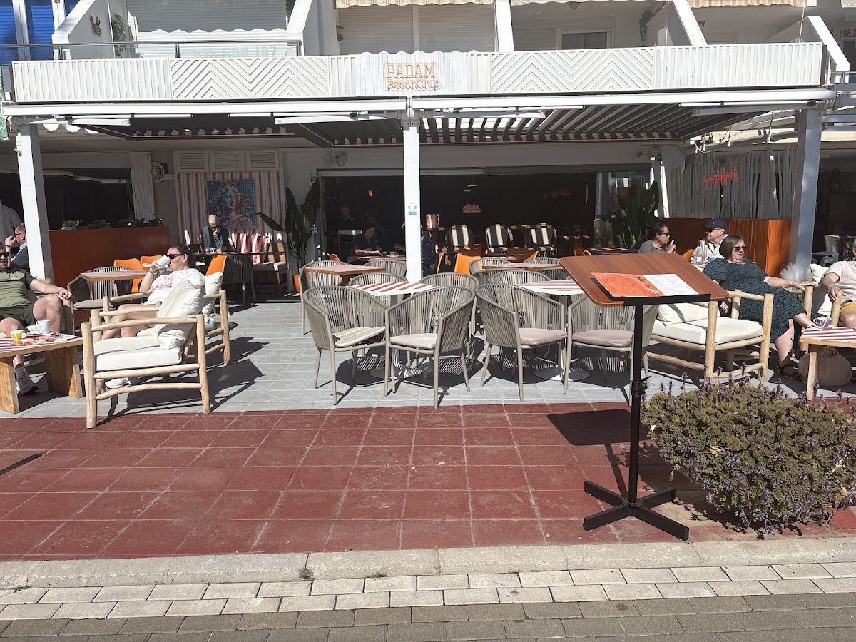 Outdoor seating area of Padam Beach restaurant with patrons enjoying their meals in a sunny setting.