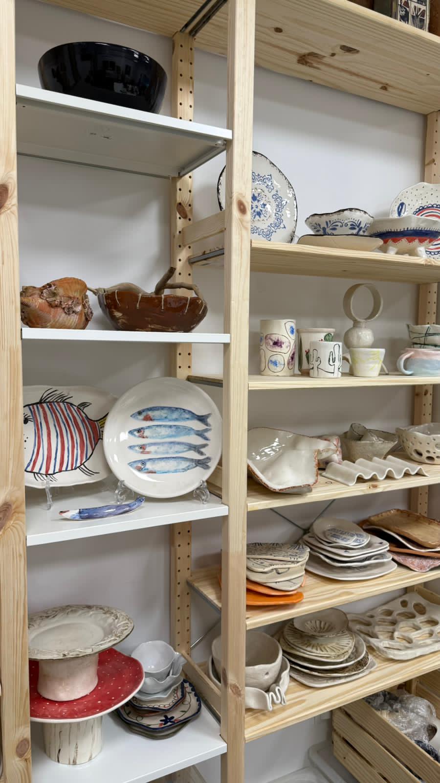 Shelves displaying various ceramic dishes, bowls, and mugs at (Pausa) cerámica in Fuengirola.