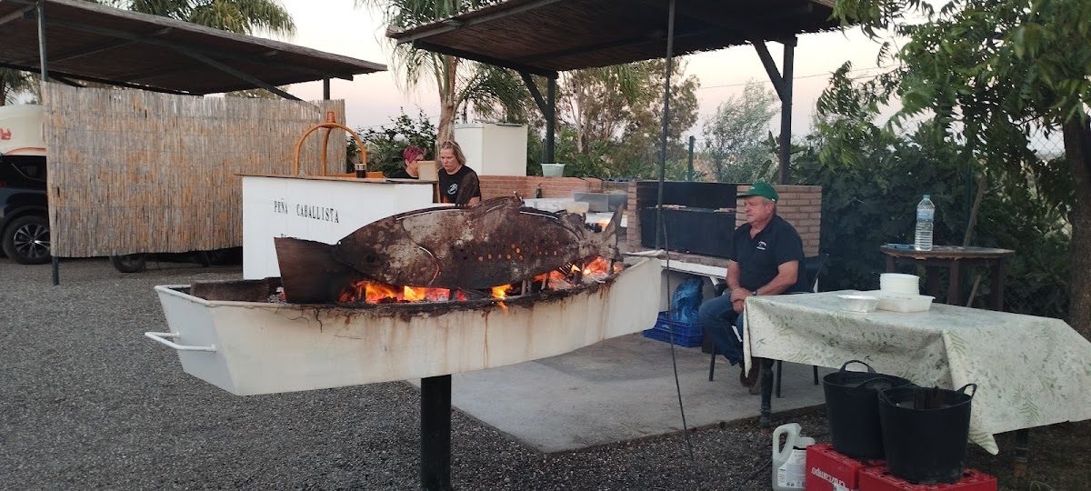Peña Caballista El Encuentro features an outdoor grill with a chef cooking over an open flame.