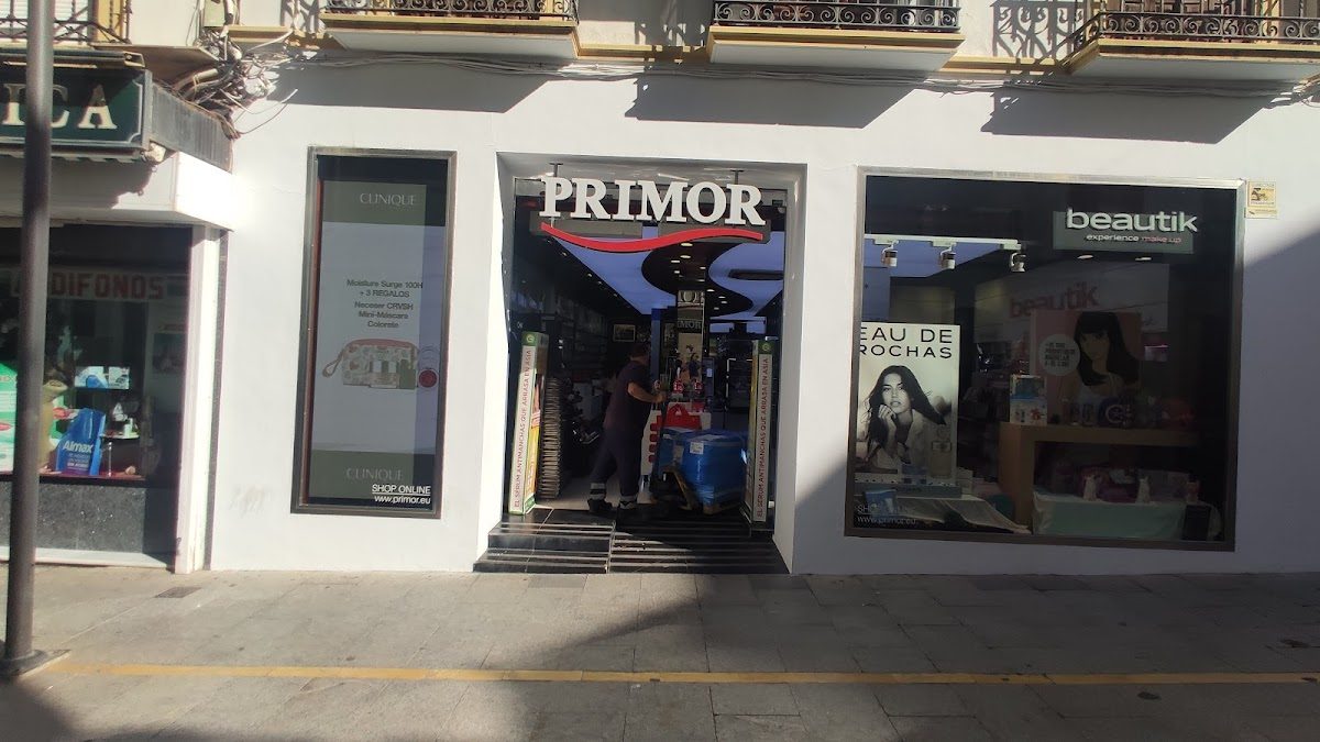 La entrada de Perfumería Primor cuenta con un letrero llamativo y expositores de productos de belleza.