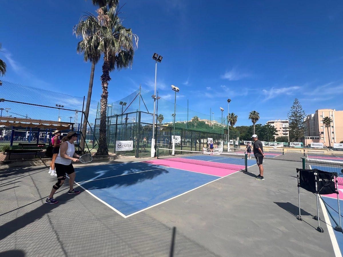 Canchas de pickleball al aire libre en el Pickleball Center de Torre del Mar, con jugadores y palmeras bajo un cielo azul despejado.