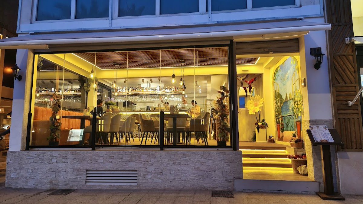 The exterior of Pizzeria Ristorante Capri features large glass windows, warm yellow lighting, and a welcoming entrance.