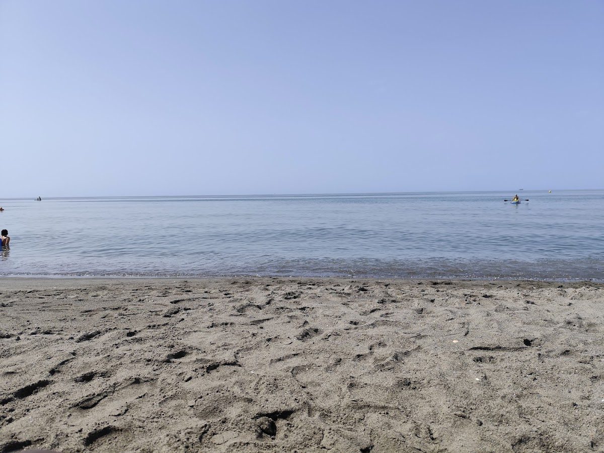 A sandy beach with calm waters and a clear sky at Playa Las Dunas in Torrox.
