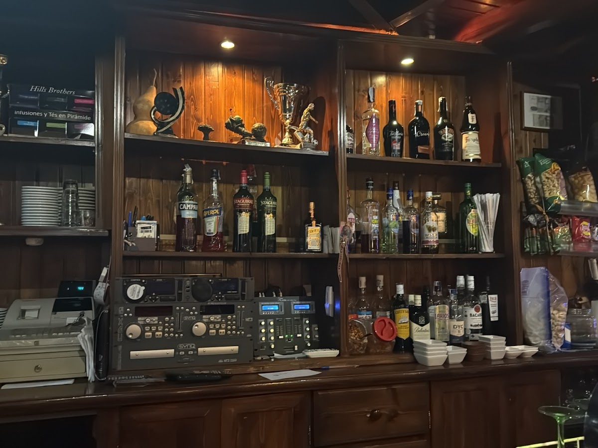 The bar at Pub El Kalero features a variety of liquor bottles, decorative items, and a sound system.