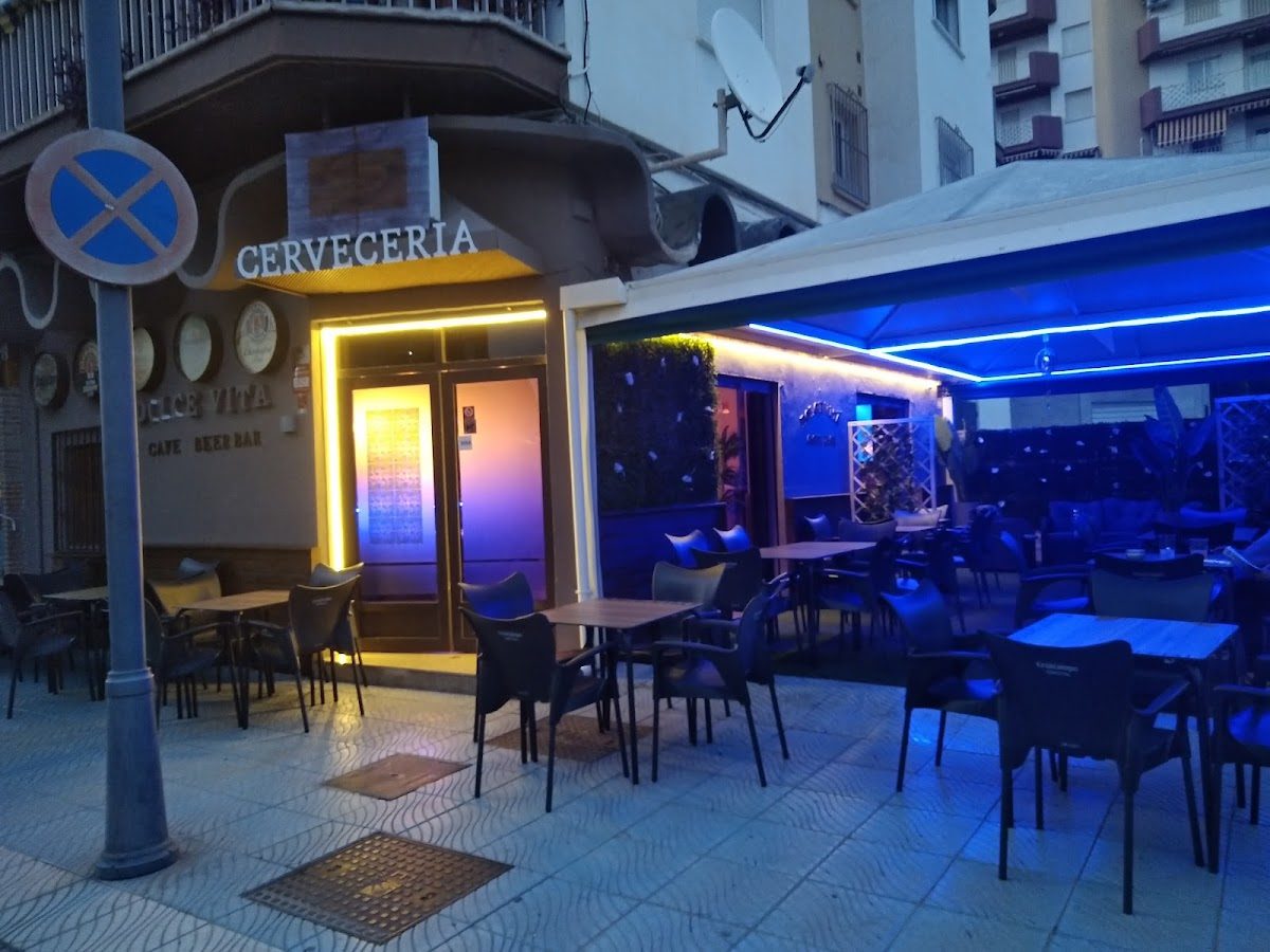 Vista exterior del pub LA CAÑA, con terraza y letreros iluminados.