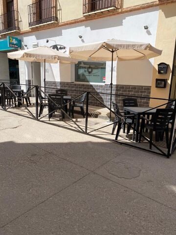 Outdoor seating area with black tables and umbrellas at Pub La Odisea in Mollina.