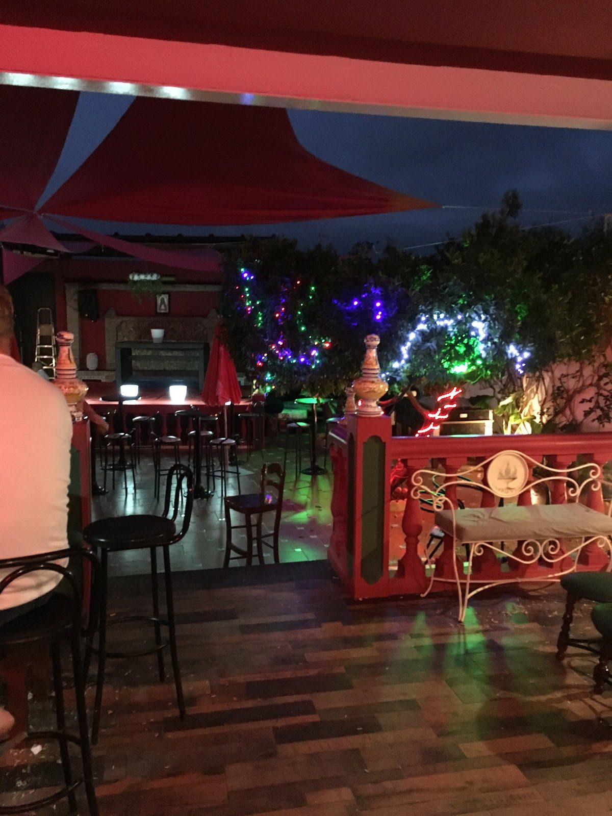 El Pub Sanchez cuenta con una vibrante zona al aire libre con luces de colores y asientos, creando un ambiente nocturno muy animado.