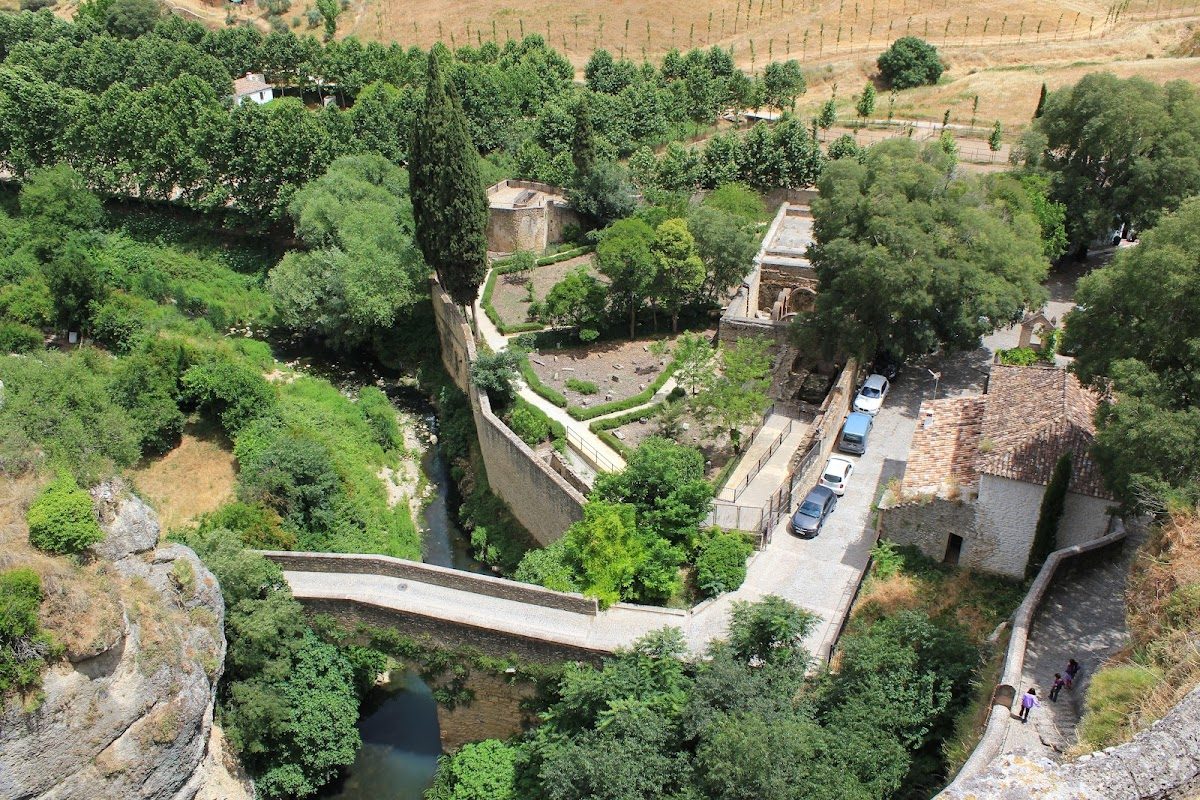 El Puente San Miguel atraviesa un valle exuberante con vegetación y una estructura histórica en Ronda, Málaga.