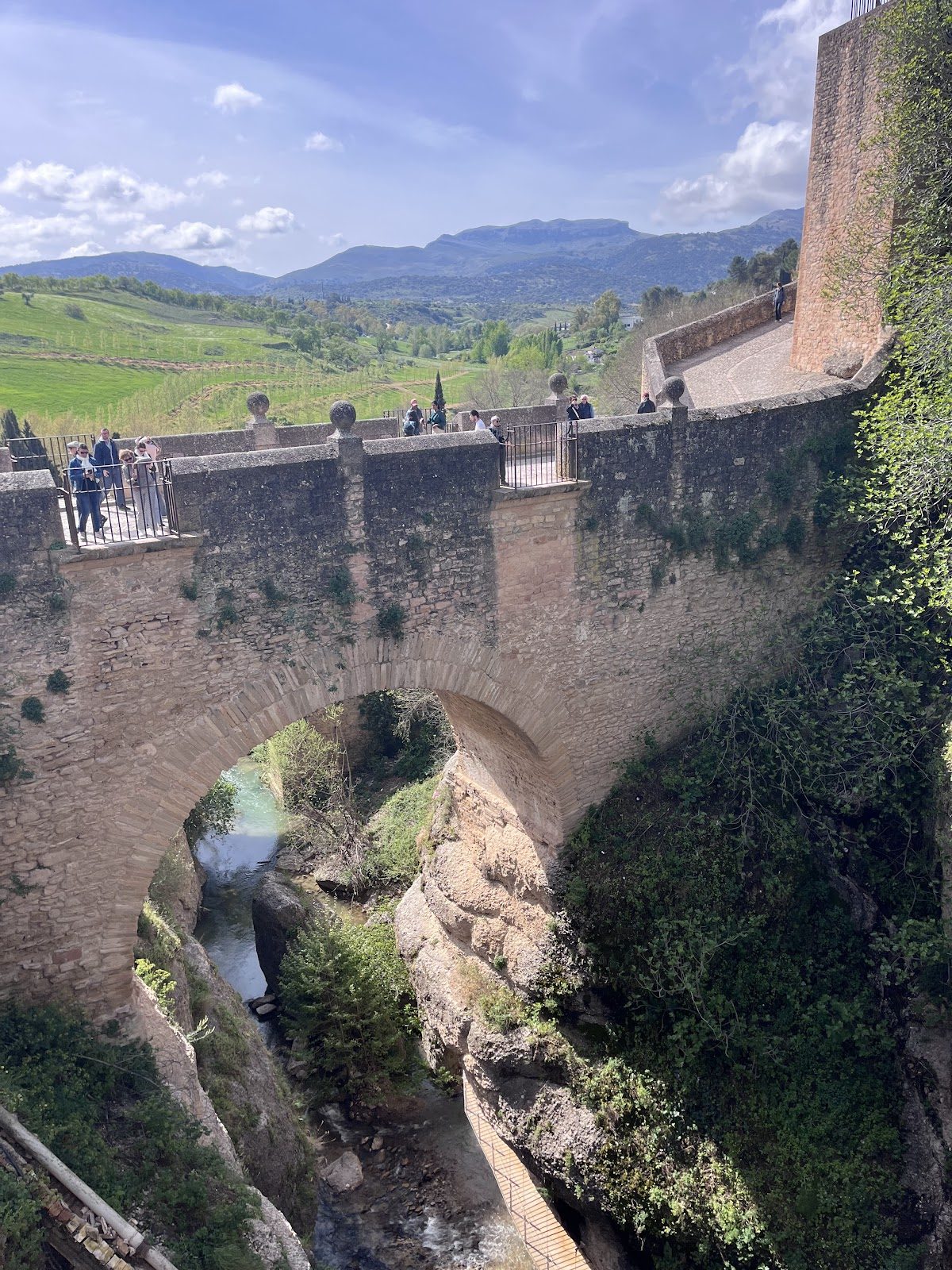 Puente Viejo es un puente histórico de piedra con vistas a un desfiladero y montañas panorámicas al fondo.