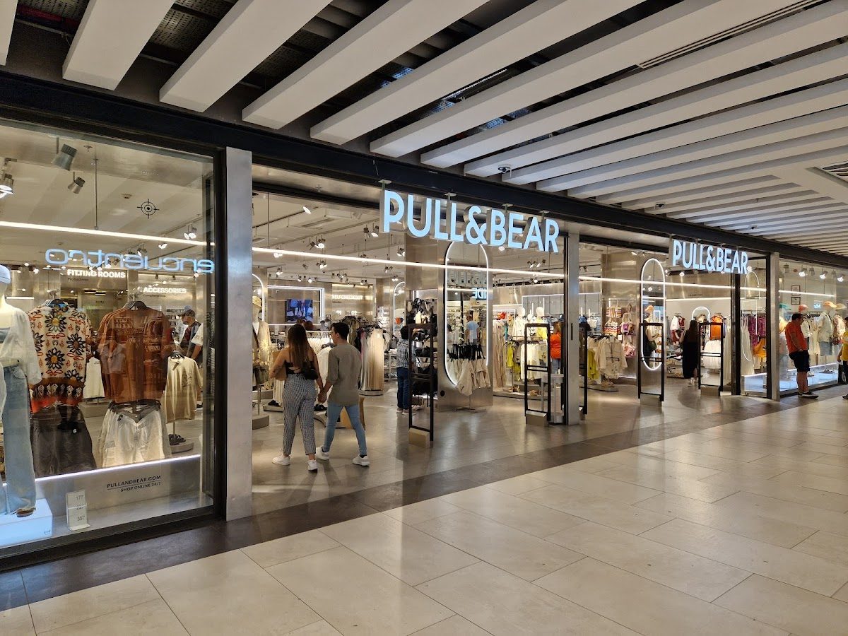 La tienda Pull&Bear presenta un exterior moderno con grandes ventanales que exhiben prendas de moda.