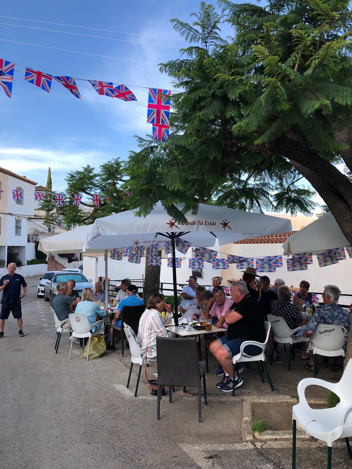 Outdoor seating area at Punta Lara Bar, with patrons enjoying drinks under British flag decorations.