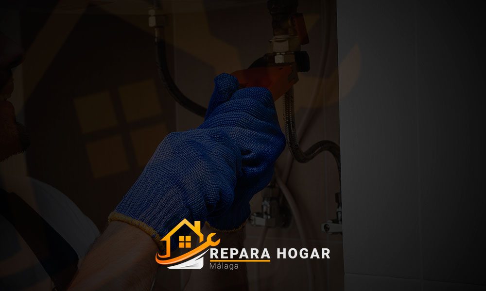 Un técnico con guantes azules repara un electrodoméstico, en el que se ve el logotipo de Reparación Hogar.