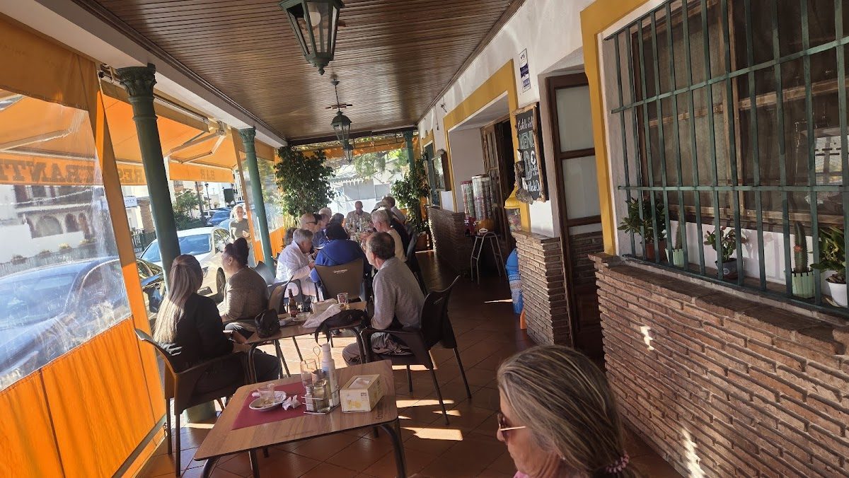 Outdoor seating area of Restaurante Bar Castillo Solis with patrons dining under orange awnings.