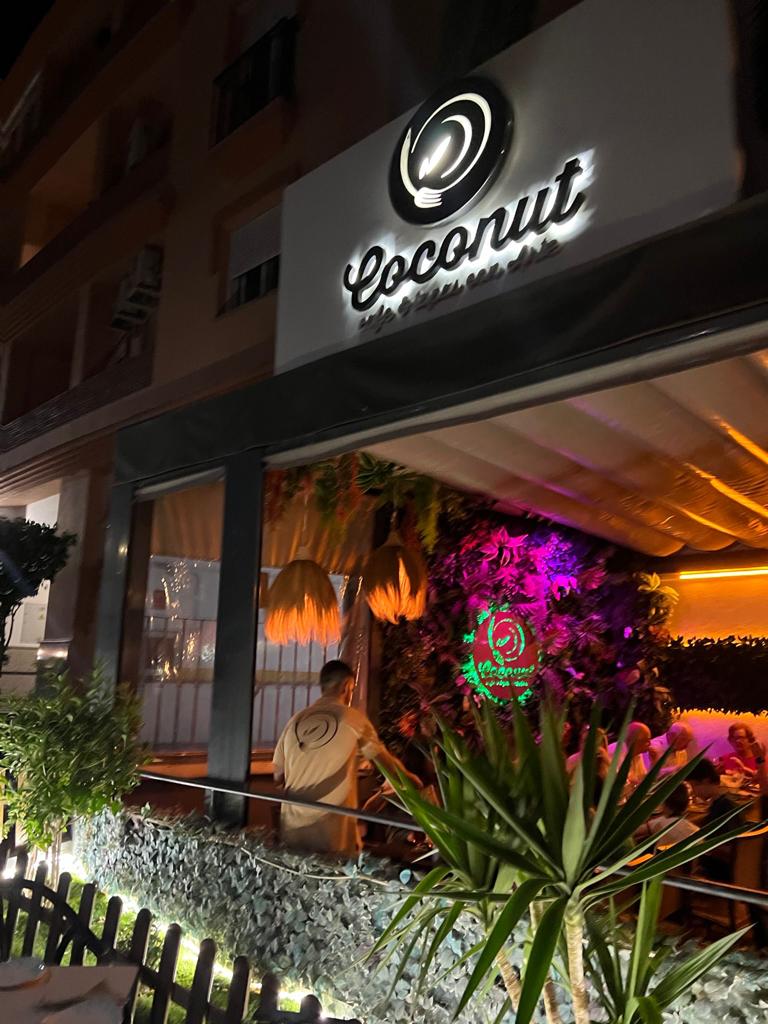 The exterior of Restaurante Coconut Tapas features a modern design with tropical decor and outdoor seating.