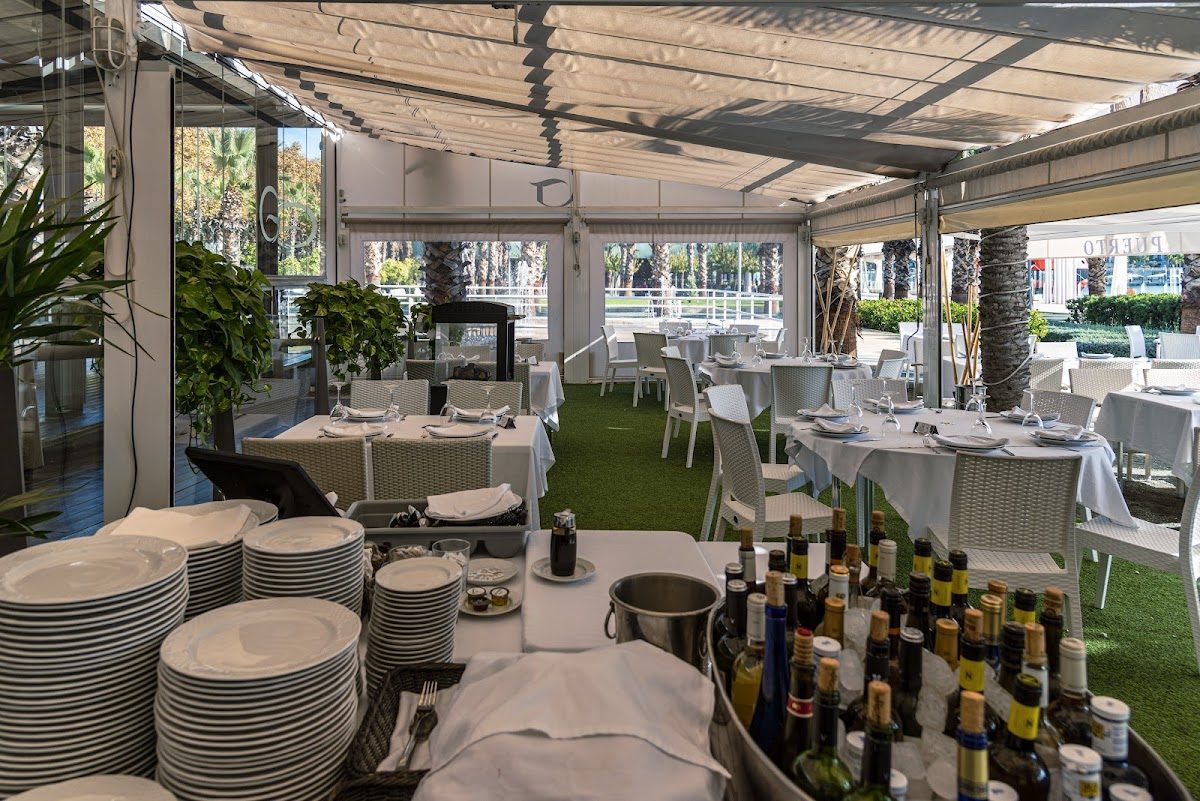 El restaurante Gutiérrez Puerto cuenta con una amplia terraza con mesas blancas y una variedad de bebidas embotelladas.