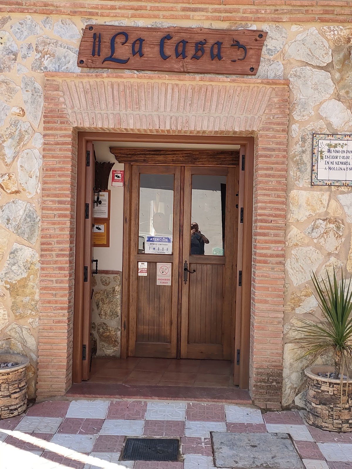 Vista exterior del restaurante "La Casa" en Mollina, con puerta de madera y paredes de piedra.