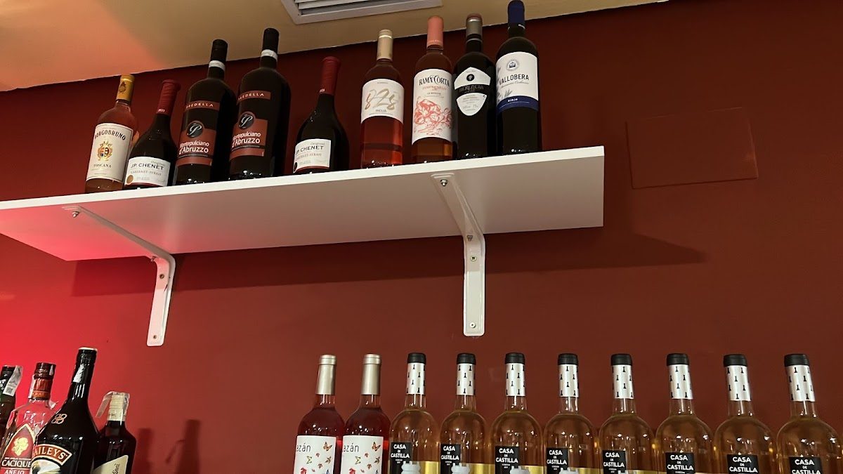 Un estante que exhibe varias botellas de vino y licores en el Restaurante La Esquina Portuguesa.