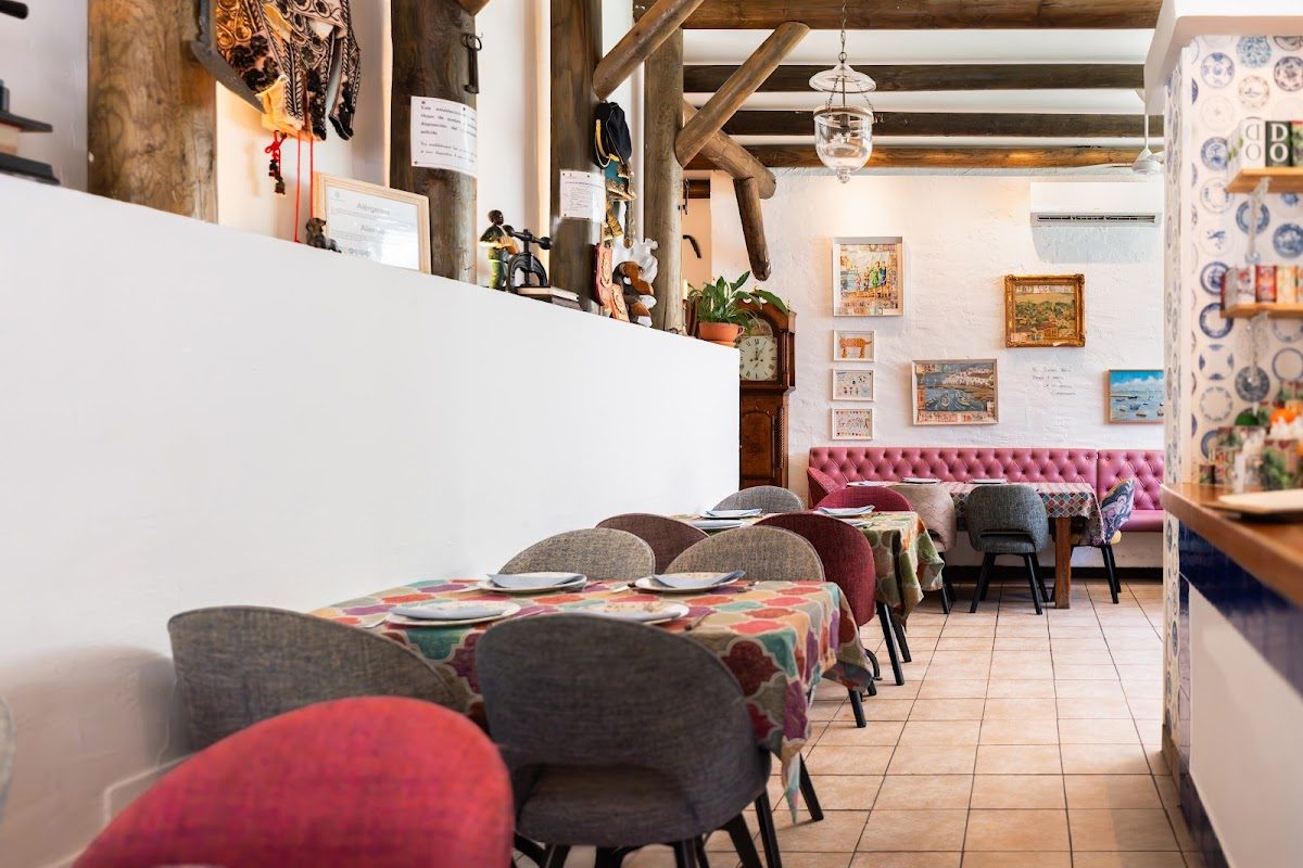 Interior del Restaurante Taberna Gaspar, con mesas coloridas, asientos mullidos y decoración rústica.