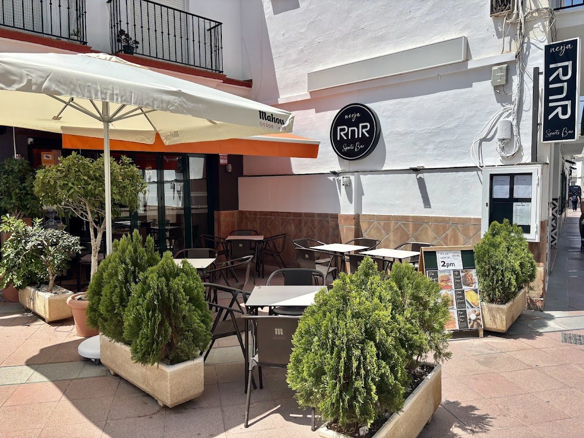 RnR Bar features outdoor seating with tables and chairs, surrounded by potted plants in Nerja.