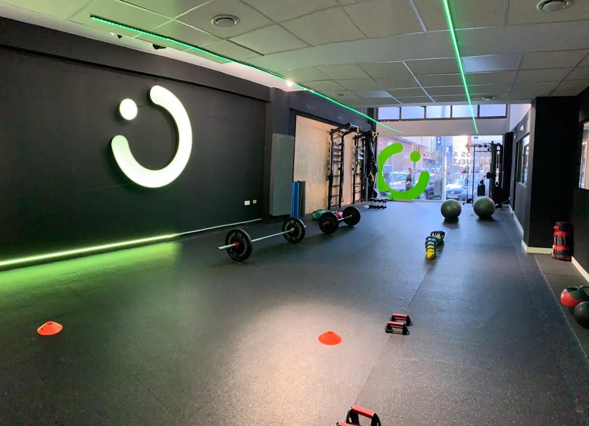 El centro de entrenamiento funcional ROUND cuenta con una amplia zona de ejercicios equipada con aparatos de fitness, pesas e iluminación vibrante.