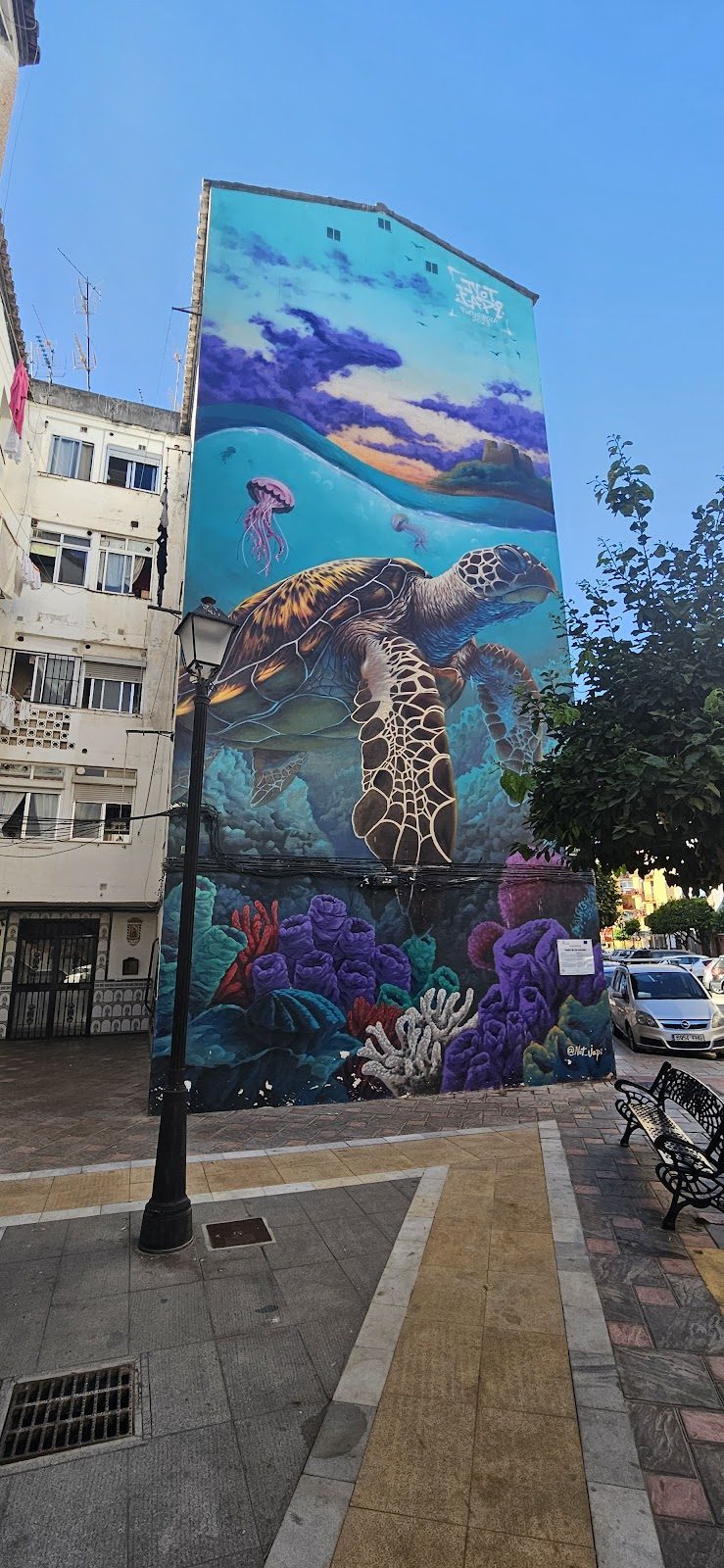 A vibrant mural of a turtle surrounded by coral and jellyfish on a building in Fuengirola.