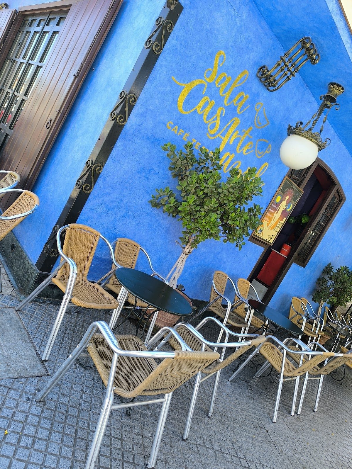 Exterior of Sala Casarte Azul featuring blue walls, outdoor seating, and decorative plants.