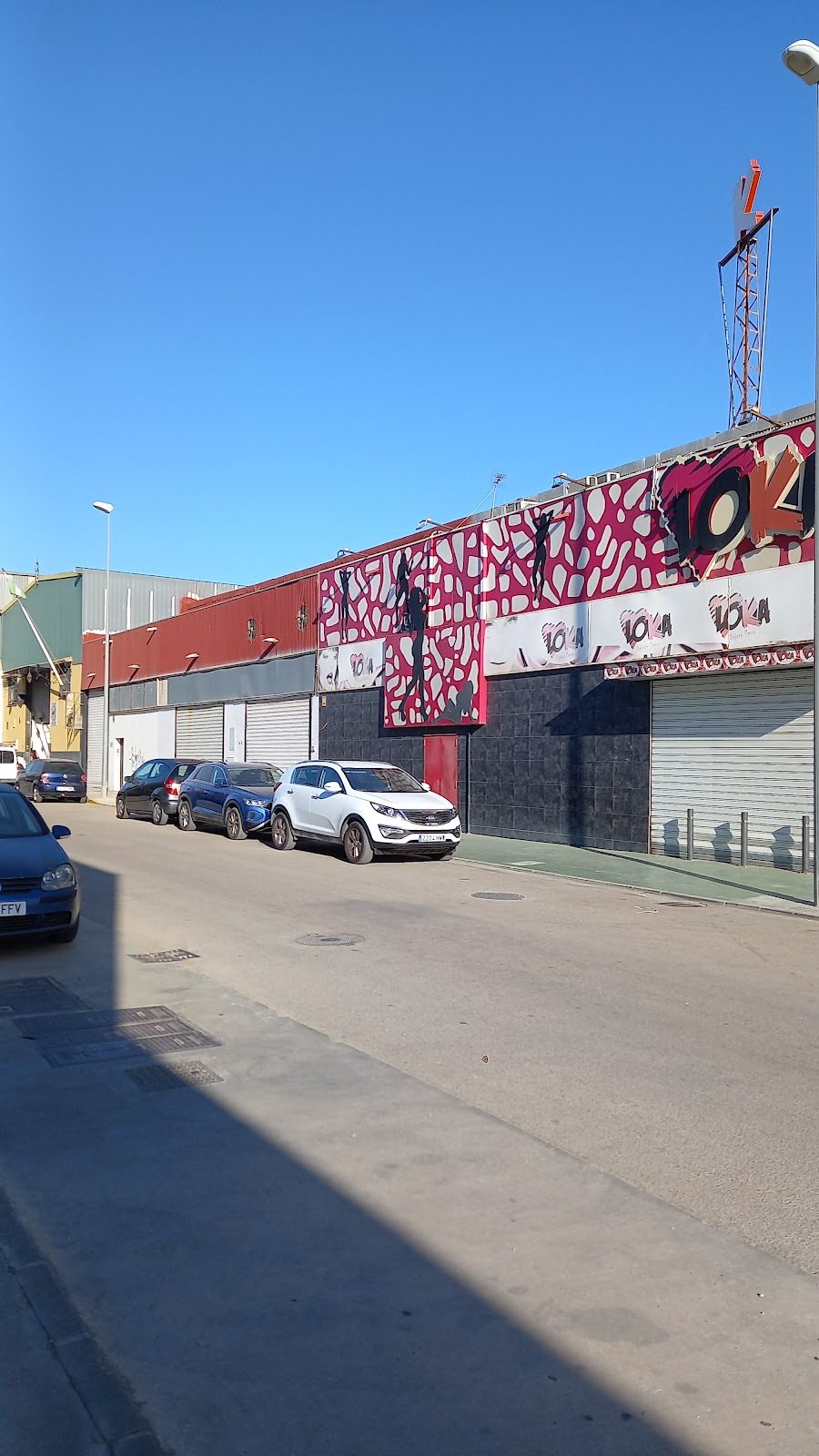 Exterior view of Sala Loka with colorful murals and parked cars along the street in Vélez-Málaga.