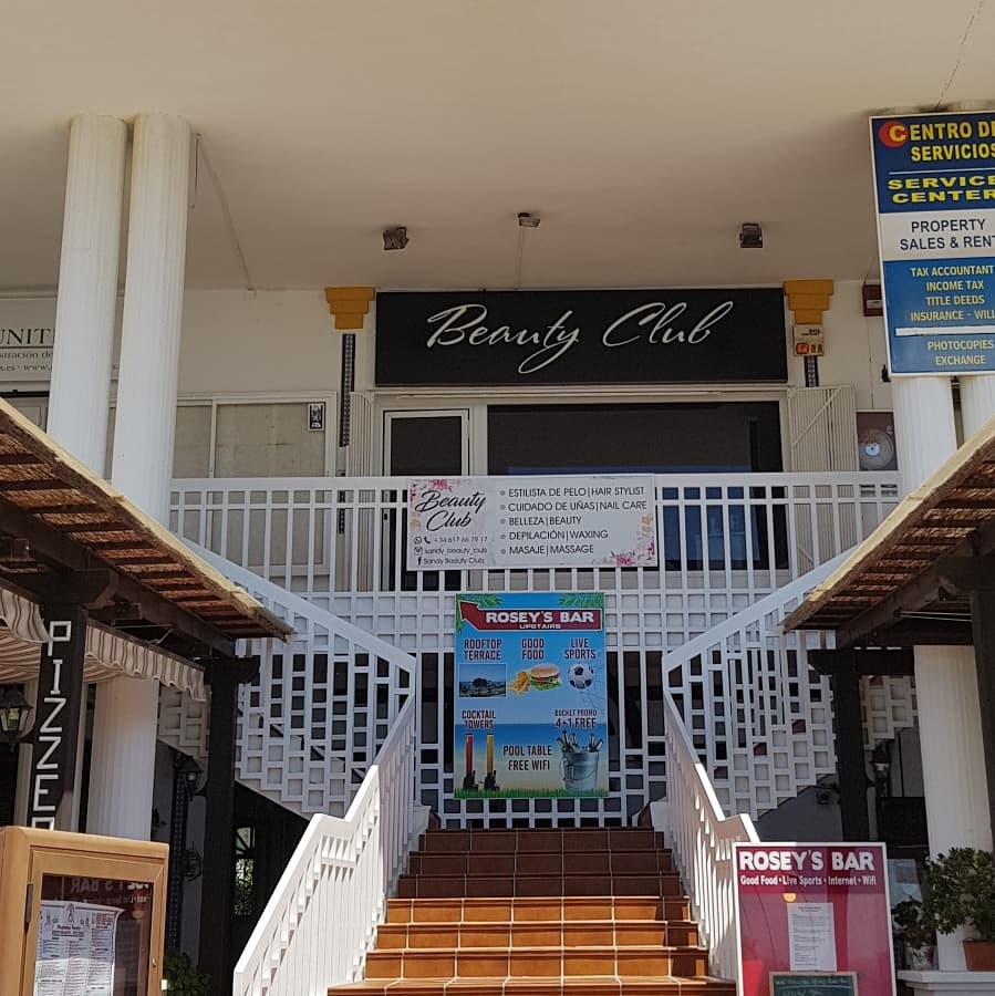 Sandy Beauty Club cuenta con una entrada acogedora con escaleras que conducen al letrero del salón de belleza.