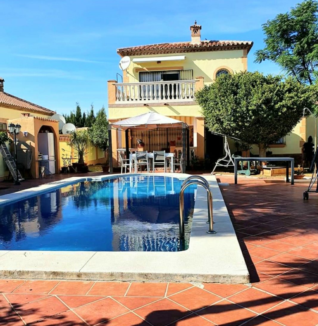 Una espaciosa villa con piscina, zona de comedor al aire libre y jardín bien cuidado.