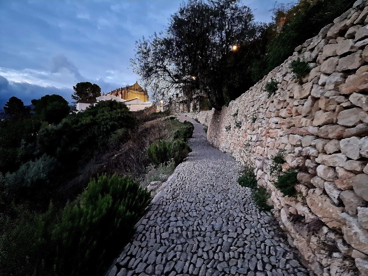 Un sinuoso camino empedrado rodeado de vegetación y muros de piedra en Ronda, Málaga.