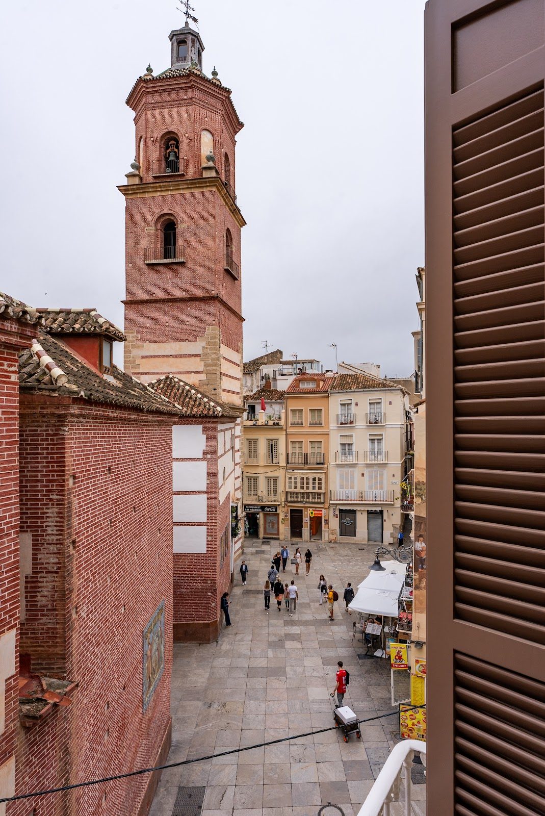 View from Smartr Málaga Centro showing a square with a bell tower and people walking.