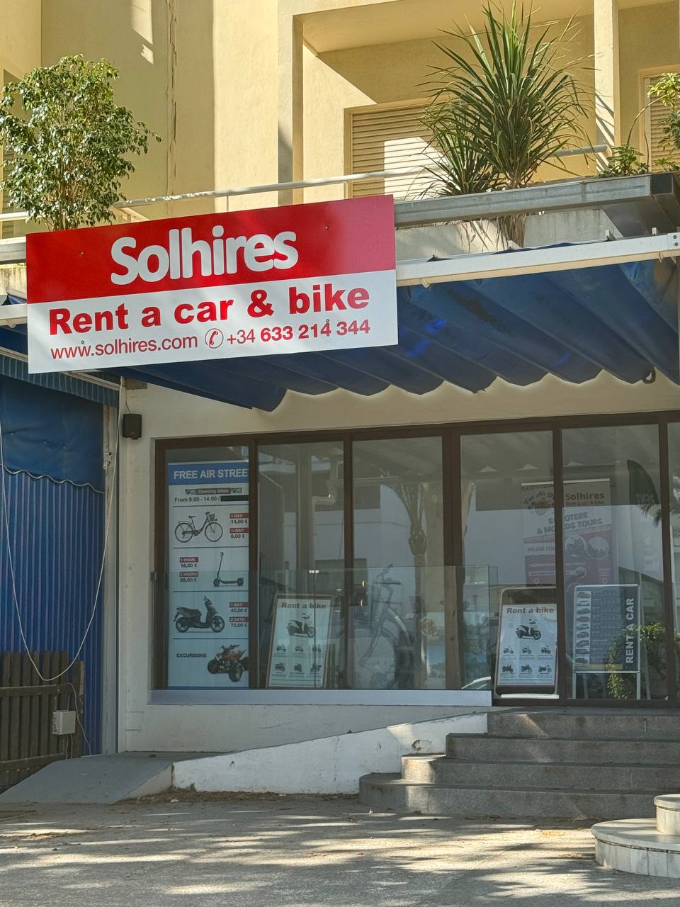 The Solhires storefront features a red sign indicating car and bike rentals, with a blue awning and large windows.