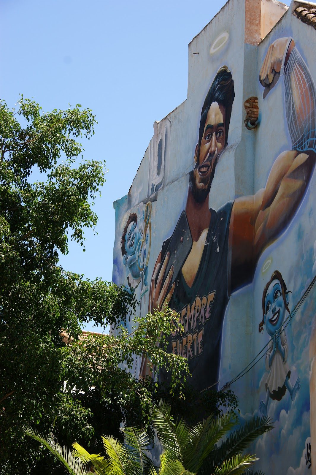 Un vibrante mural que representa a un hombre sonriente sosteniendo un teléfono, rodeado de vegetación y coloridos personajes.