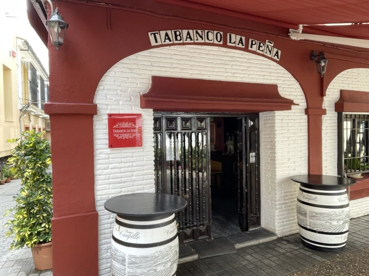 Entrance of Tabanco "La Peña" featuring a white brick facade and outdoor tables.