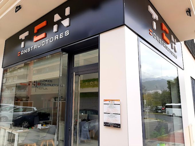 The exterior of TCN Constructores features a modern design with a glass entrance and prominent signage.