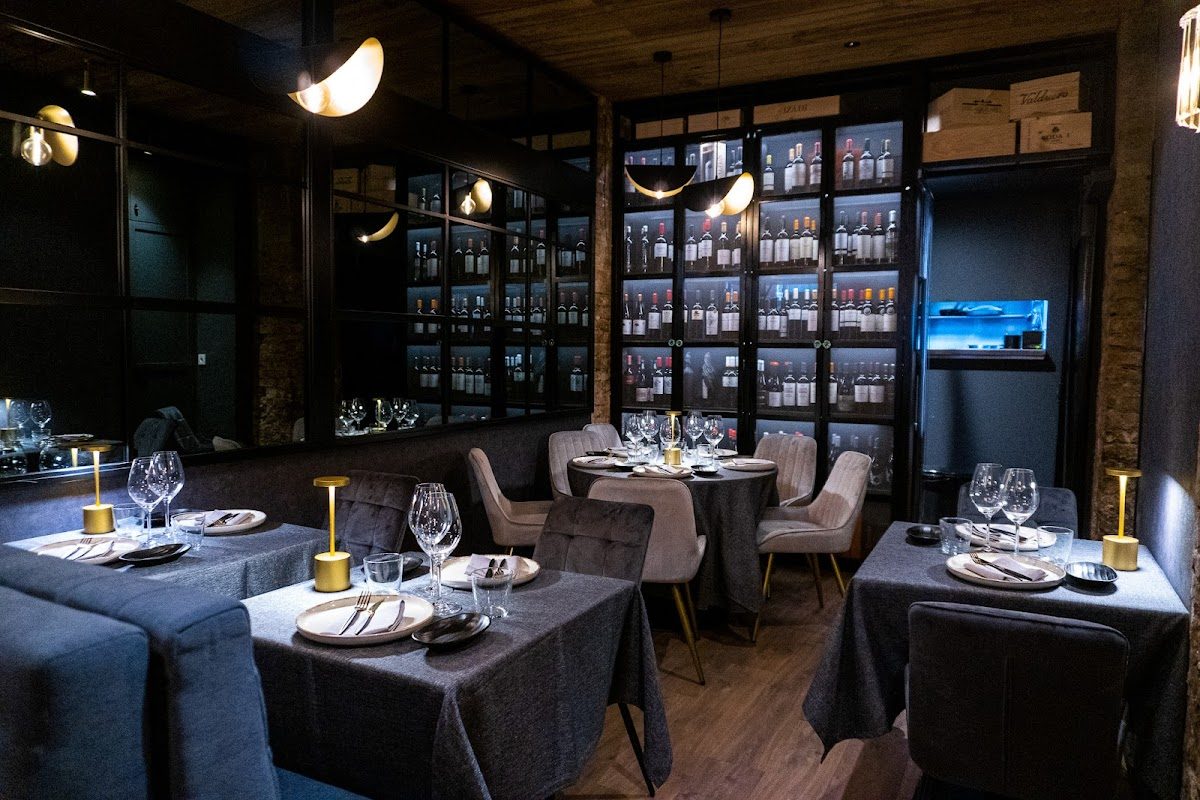Elegante comedor en el restaurante Temple, con mesas con estilo, cristalería y una vitrina de vinos al fondo.