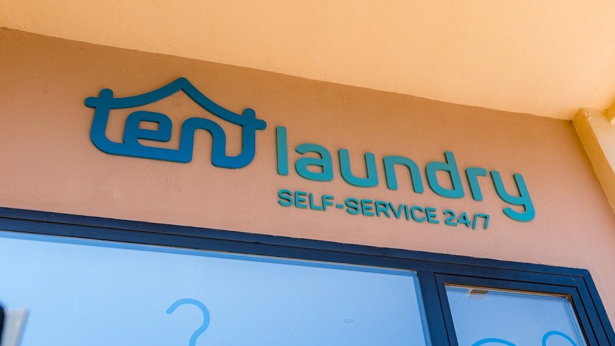 En el exterior de la lavandería de carpas en Torremolinos se puede ver un llamativo letrero azul con la leyenda "autoservicio 24/7".