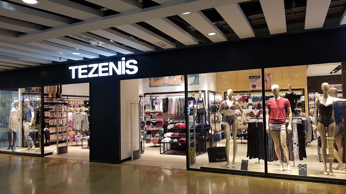 La fachada de la tienda Tezenis presenta maniquíes vestidos con diversas prendas de vestir y un escaparate interior bien surtido.