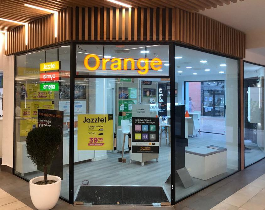 Fachada de la tienda Tienda Orange con llamativos letreros y carteles promocionales en Carrefour, CC Los Patios, Málaga.