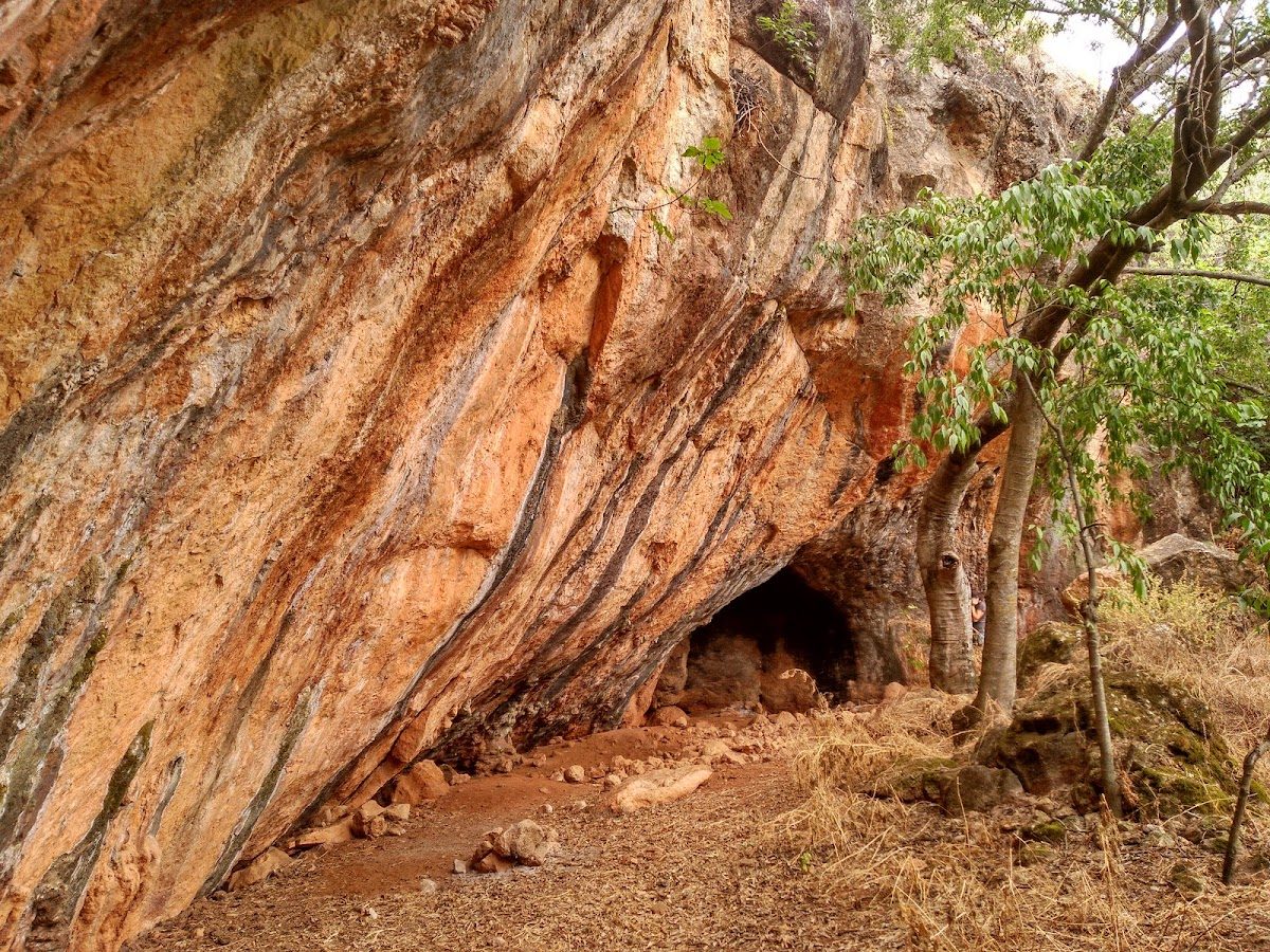Torca de Mollina presenta una gran entrada rocosa rodeada de vegetación natural en un paisaje agreste.