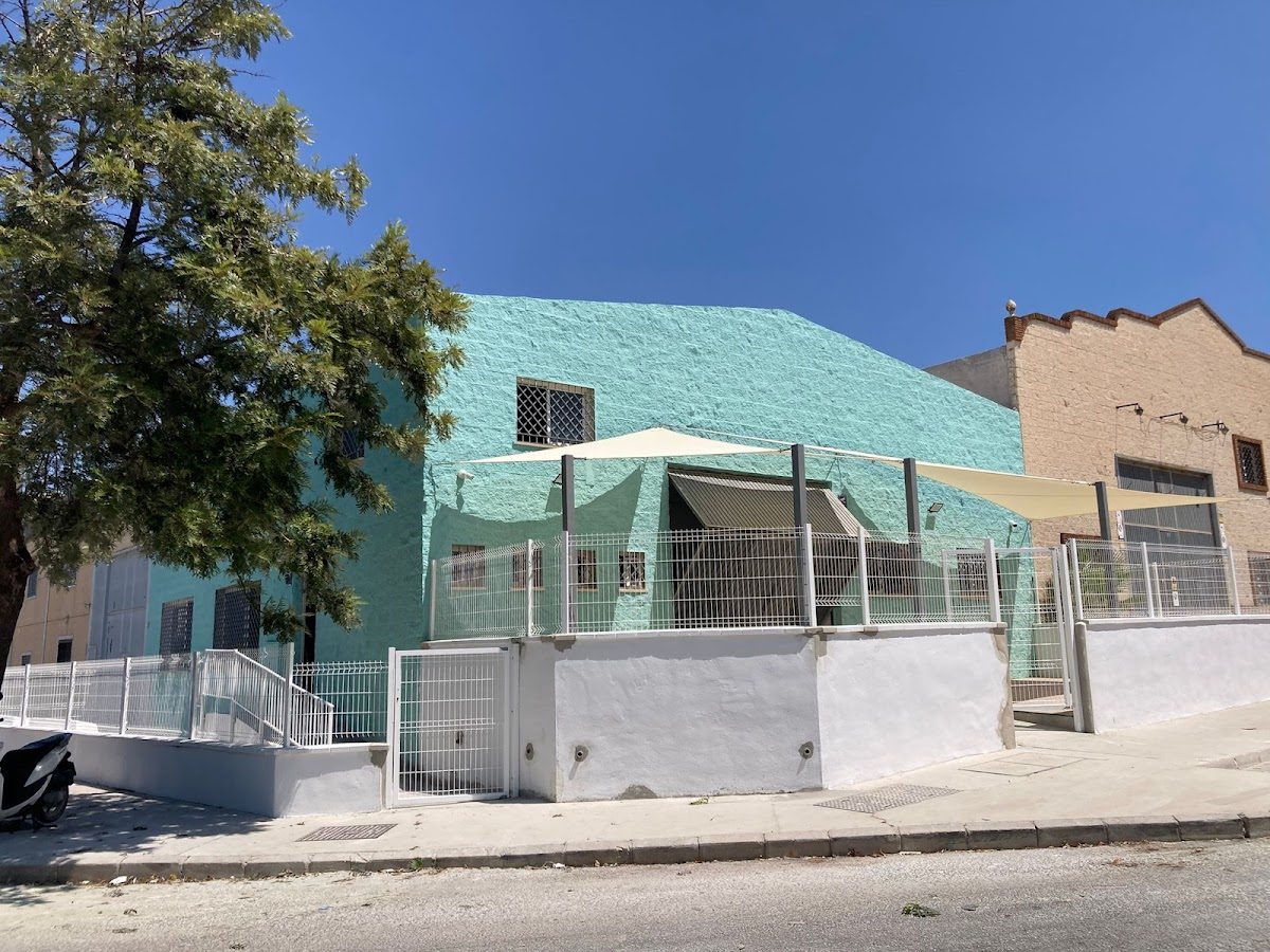 Vista exterior del centro de entrenamiento VANKO ALHAURIN, que muestra un edificio de color verde menta y una zona exterior sombreada.