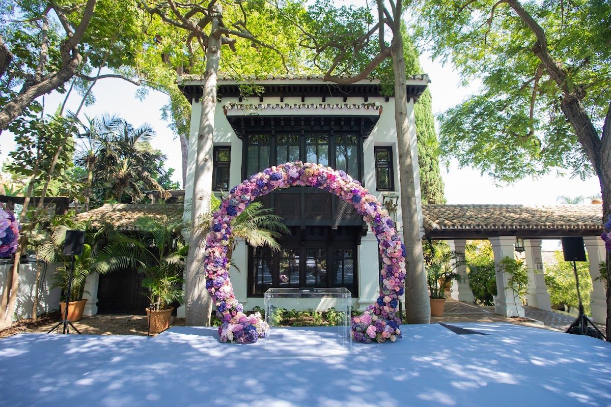Un precioso espacio para bodas al aire libre, decorado con un arco floral y exuberante vegetación, en Tucco Weddings and Unique Affairs.